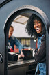 © Maskot - Happy mature female owner with curly hair standing near door of food truck