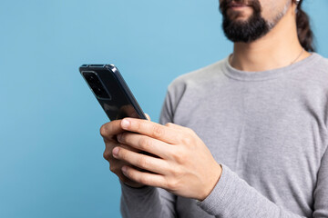 casual and confident young man using smartphone in front of the camera, solving freelancing tasks on