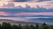 © Richafuji - Panoramic view of a misty forest and rolling hills under a dramatic sunset sky with pink and blue hues. The scene evokes tranquility and vastness.