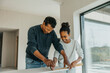 © Maskot - Grandfather teaching granddaughter to measure wooden plank while renovating house