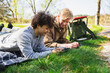 © Diego Martin/Stocksy - Young friends Using Phone While Relaxing on Picnic Blanket Outdoors