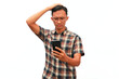 © Isman - An Asian man looks at his cell phone with a confused expression.