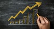 © Ado - Hand drawing a growing chart on a dark chalkboard. A yellow upward trend line connects a series of gray bar graphs