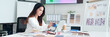 © Pichsakul - Asian Interior Designer at Work Selecting Color Palette and Material Samples for Home Design Project Online Using Laptop in Modern Office Space