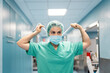 © Santi Nuñez/Stocksy - Female surgeon putting on surgical mask in hospital corridor