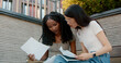 © Danil Nevsky/Stocksy - Two young students reviewing notes together outdoors