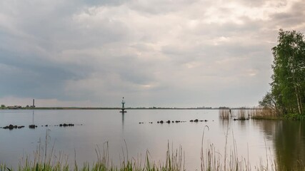 Sticker - Lakeside timelapse with cloudy sky, moving boat, lighthouse, reeds and distant an old steam pumping station silhouette at dusk. Timelapse.