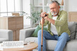 © Pixel-Shot - Senior man with stick suffering from Parkinson syndrome on sofa at home