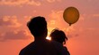 © Hamky - Silhouette of a young couple with balloon at sunset background.