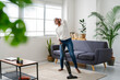 © Westend61 - Carefree woman vacuum-cleaning and listening to music with headphones at home