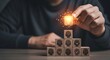 © Ali Raza - Conceptual thinker placing a radiant light bulb block atop wooden blocks etched with cognitive profiles against a dusky