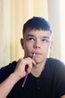 © dizfoto1973 - Thoughtful young person with pencil in mouth, looking up, pondering or studying. Close-up portrait capturing concentration and introspection.