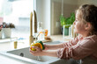 © Kristina89 - Little cute girl of 7 years old washes vegetables under the tap in the kitchen. Healthy food.