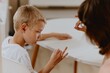© looking2thesky - Young mother helps her hard-of-hearing son with schoolwork at home. A natural, heartfelt moment of inclusion, care, and rehabilitation, highlighting love, support, and everyday learning