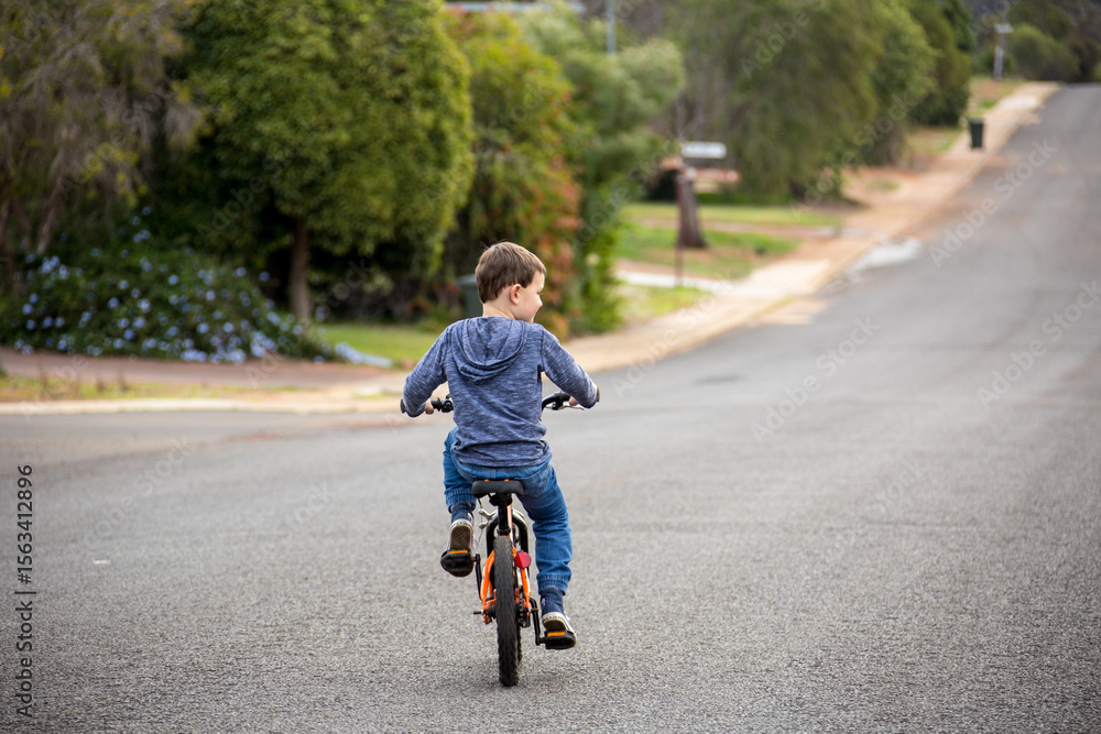 Child riding bike on road with no helmet Stock Photo | Adobe Stock