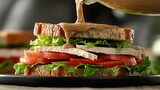 Thousand Island dressing being poured onto a sandwich, with layers of lettuce, tomato, and sliced turkey visible in the shot.