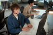 © Leny Studio - Two young professionals working modern office environment, focusing customer support tasks. One is wearing headset, typing keyboard, and engaging tech related assistance, while other works laptop