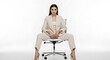 © robbi - Confident Young Businesswoman in Elegant Pantsuit Sitting on Office Chair with Empowered Pose Against White Background