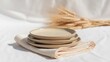 © Muhammad - Elegant Stack of Handmade Ceramic Plates on Linen with Natural Wheat Decor