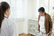 © Ekkasit A Siam - Asian female doctor closely observing elderly woman attempting to walk with walker, supporting recovery and rehabilitation after joint pain in professional medical therapy room