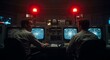 © Raul - Two men are working at control panels filled with radar screens and red alert lights in a dimly lit room.