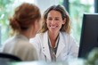 © aryuna99 - A smiling female doctor in a white coat sits at a desk, attentively listening to a female patient during a consultation in a bright, modern office