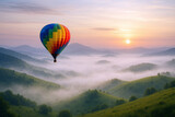 Colorful hot air balloon drifting over misty green mountain valleys at sunrise image