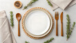© Abid Ur Rehman - Table Setting Elegance: A top-down view of an empty plate, a warm and inviting scene. Featuring a placemat, fork, knife, spoon, and sprigs of rosemary and peppercorns, creating a beautiful.