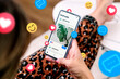 © AlexPhotoStock - Social media ads on a mobile phone screen with emojis. A woman with a smartphone showing an example of a social media ad.