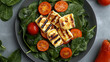 © Hina - Minimalist top view of a modern salad with warm grilled halloumi over a bed of baby spinach, cherry tomatoes, and orange baked pepper slices on a matte grey tabletop