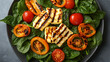 © Hina - Minimalist top view of a modern salad with warm grilled halloumi over a bed of baby spinach, cherry tomatoes, and orange baked pepper slices on a matte grey tabletop
