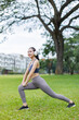 © David - Portrait of a smiling young fitness asian girl doing stretching in the park.Healthy women exercise concept.