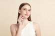 © kitthanes  - A beautiful young woman with clean, fresh skin against a beige background. Skincare, facial treatment, cosmetology, beauty, and spa. An elegant portrait of an woman.
