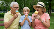 © ZUZU - Grandparents and grandchild enjoying ice cream outdoors