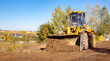 © Hanna - Yellow bulldozer at a construction site. Big wheel excavator leveling and clearing the land plot side view. Moving earthworks soil. Copy space. Building area. Special transport. High quality photo.