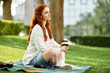 © Bliss - Relaxing outdoors with a warm drink, a young woman enjoys her spare time in the park