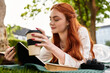 © Bliss - Relaxing afternoon of a beautiful young woman enjoying coffee and reading in a park