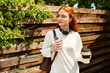 © Bliss - Young woman enjoys a peaceful moment with coffee while strolling in a serene outdoor setting