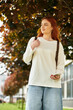 © Bliss - Young woman enjoying a sunny day under vibrant autumn trees in a city park