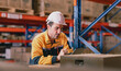 © Nassorn - Warehouse manager, store inspector checking stock on storage shelf from inventory checklist. Two diverse ethnic people wear safety hard hat working together examining merchandise at distribution store