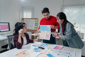 three asian ux designers working together in a modern office, analyzing and discussing mobile app in