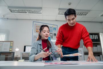 two young asian colleagues collaborating on a new mobile application, discussing wireframes and prot