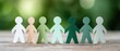 © Ryzhkov - Diverse Paper Cut-Out Figures Holding Hands on Wood with Greenery Background for Corporate Teamwork and Inclusive Wellness Event Promotion