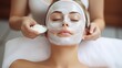 © tanveer - Close-up portrait of beautiful woman getting a gentle facial massage by a beautician. Cosmetologist applying treatment face mask On woman face. Spa treatments, Face peeling mask, facial care.