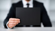 © Chaiwit - Black blank card held by businessman suit and tie, close up of hand showing empty space for text or design with confident