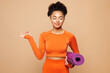 © ViDi Studio - Young fitness trainer instructor sporty woman wear orange clothes spend time in home gym hold purple yoga mat do om gesture meditate isolated on plain beige background. Workout sport fit abs concept.