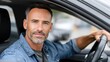 © lililia - Man with a beard sits in the drivers seat, focused on the camera, holding the steering wheel during daylight, exuding confidence and style