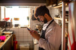 © Marko Geber - Chef using smartphone in restaurant kitchen during work