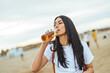 © Dragana Gordic - Woman Enjoying a Refreshing Beverage on a Serene Beach Setting