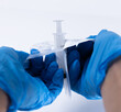 © מריה צ'וניאק - Close-up of gloved hands opening the sterile packaging of a disposable syringe. Essential preparation step in clinical, hospital, or pharmaceutical environments.